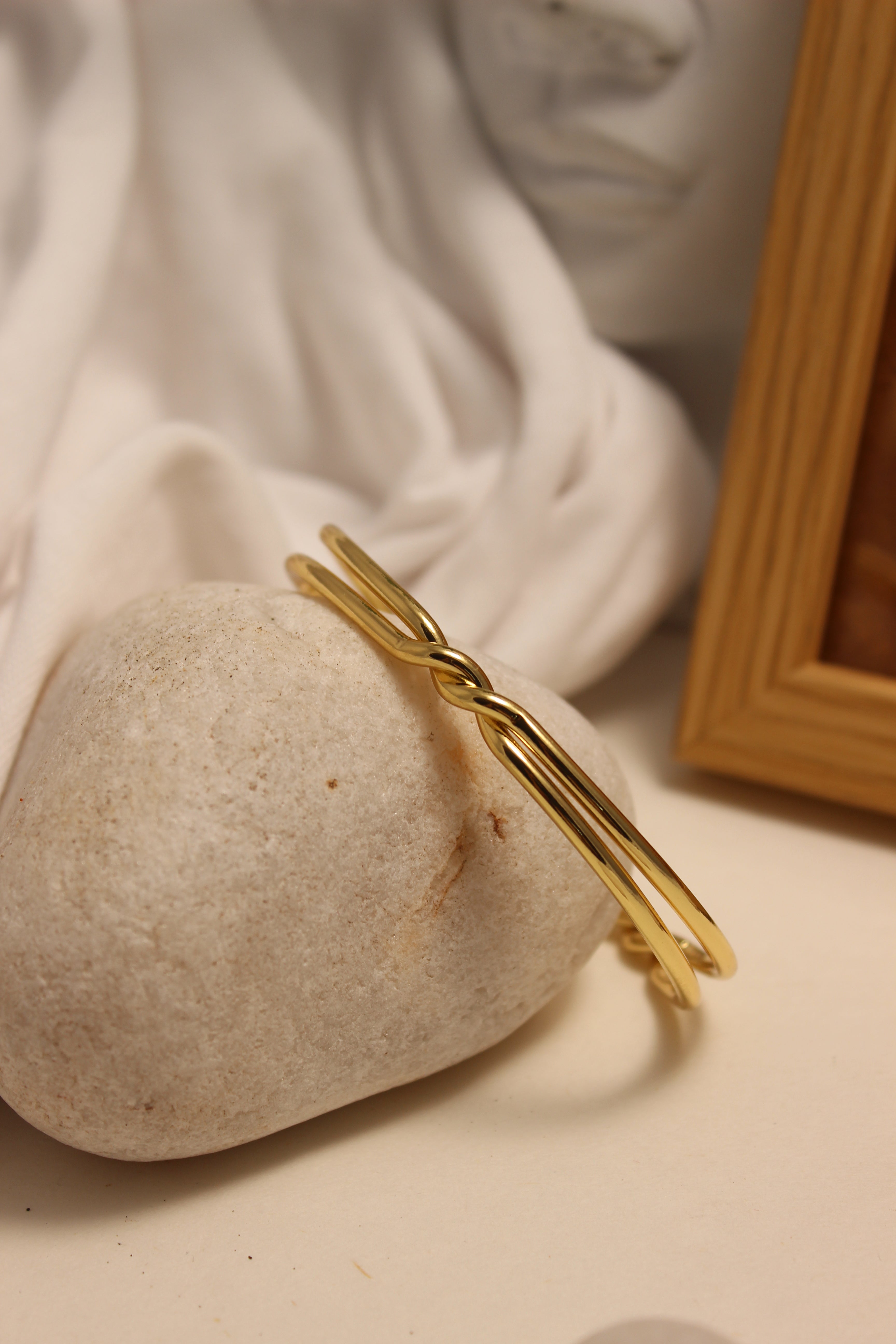 Nexus Cuff Bracelet on a beige stone with a blurred wooden frame in the background