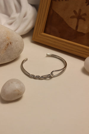 Sterling Dualis Cuff Bracelet on a surface with stones and a framed picture in the background