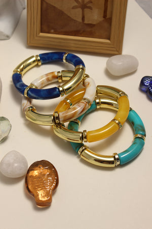 Seaglass Bangle Bracelets on a textured surface with a wooden frame and stones