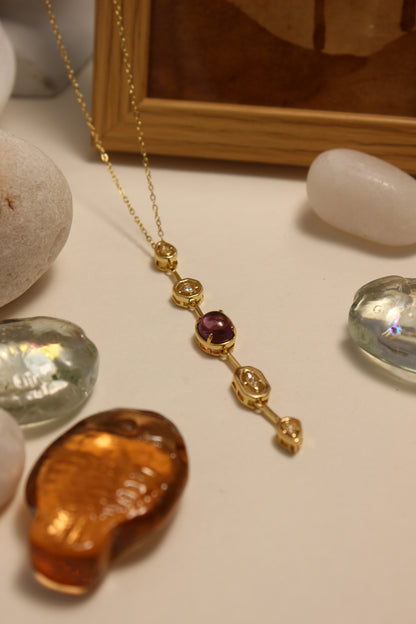 Viola Cascade Necklace on a surface with stones, seashells and wooden frame
