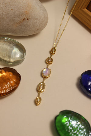 Seraphine Necklace on a surface with stones and a colorful seashells