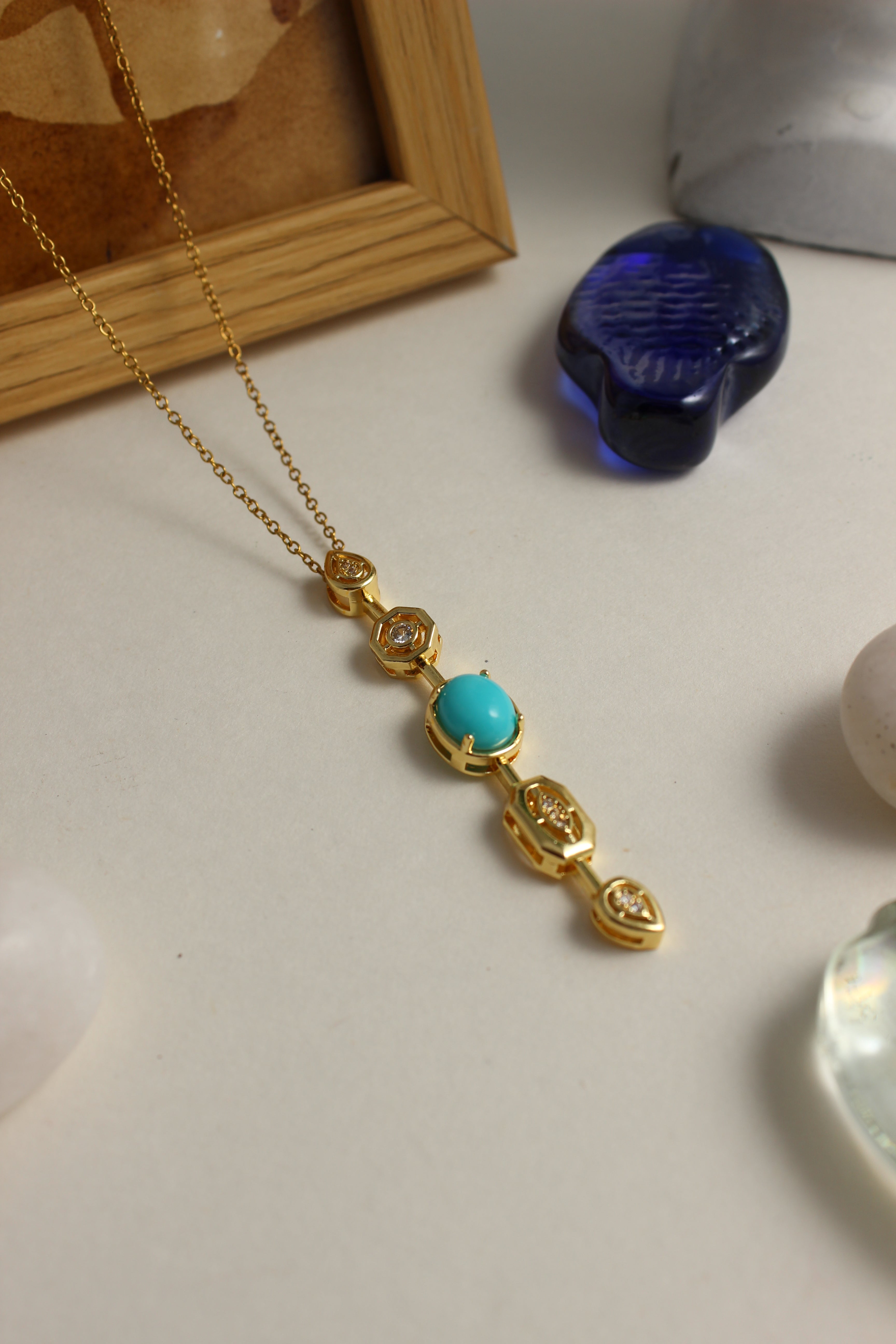 Medina Moon Necklace with a turquoise stone on a light surface