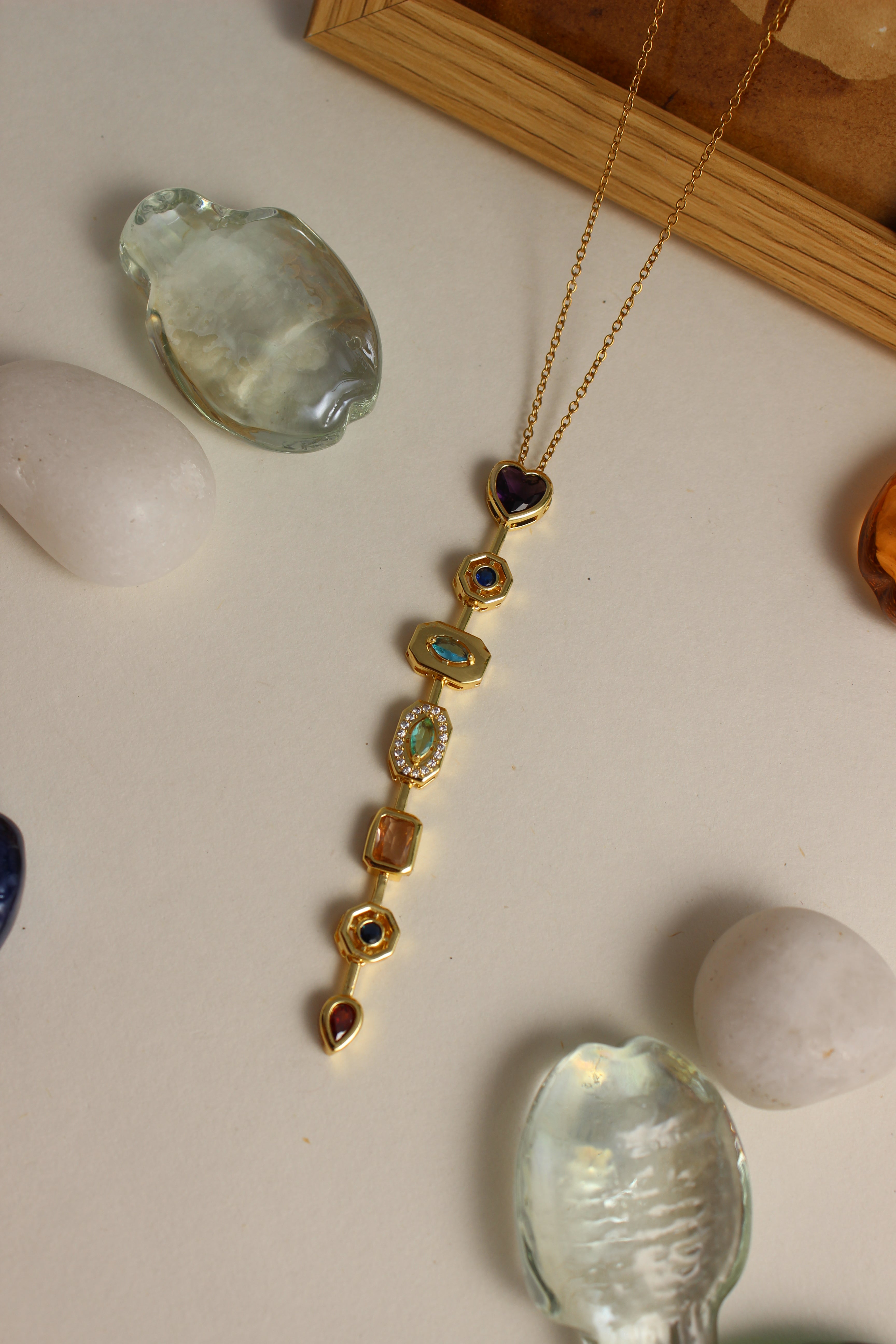 Amour Pour Necklace with gemstones on a light surface