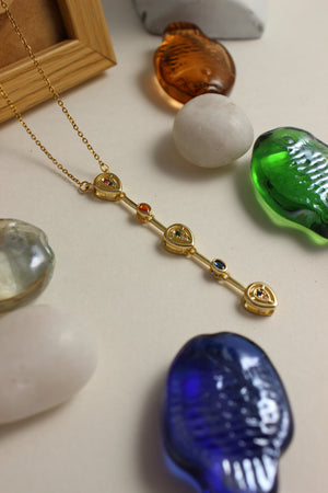 Serene Pour Necklace on a light surface with decorative seashell and stones
