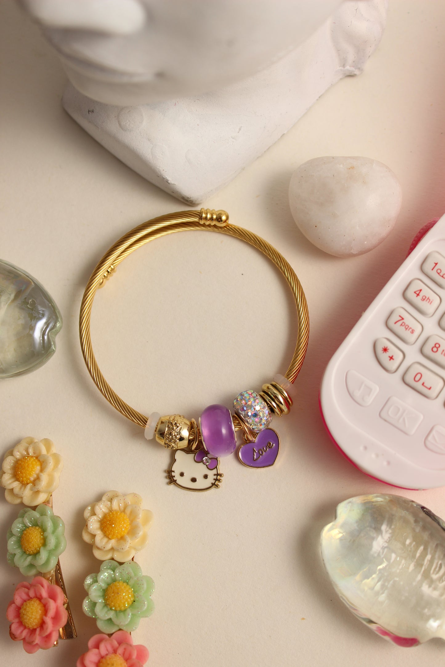 Violet Purr Bracelet with charms on a pink surface