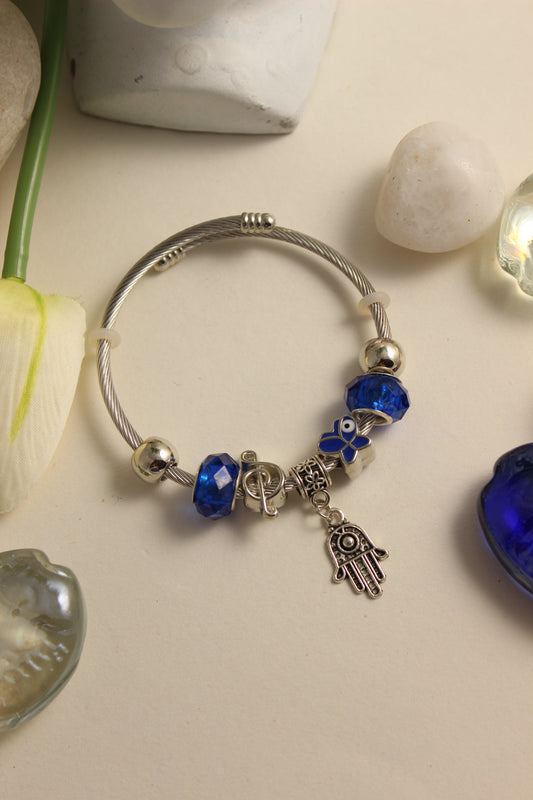 Mystic Iris Bracelet with blue beads and charms on a light surface with decorative stones
