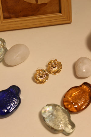 Sunset in Bloom Stud Earrings on a beige surface with decorative stones and seashells