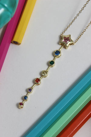 Nova Drip Necklace with colorful gemstones on a white background with colorful pencils