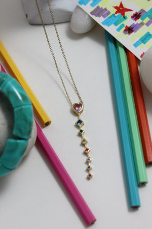 Rose Descent Necklace with colorful beads on a white surface with colorful pencils and a card
