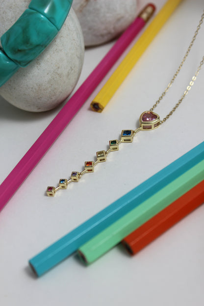 Rose Descent Necklace with gemstones on a white surface with colorful pencils