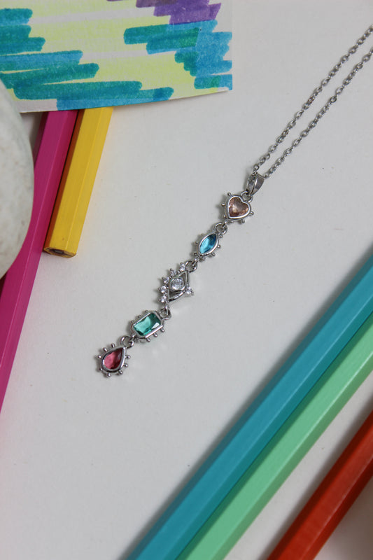 Moonlit Fortuna Necklace with colorful gemstones on a white background with colorful pencils and paper