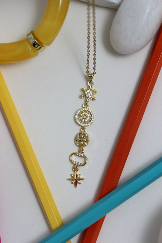 Northbloom Necklace with decorative charms on a white surface with colorful pencils