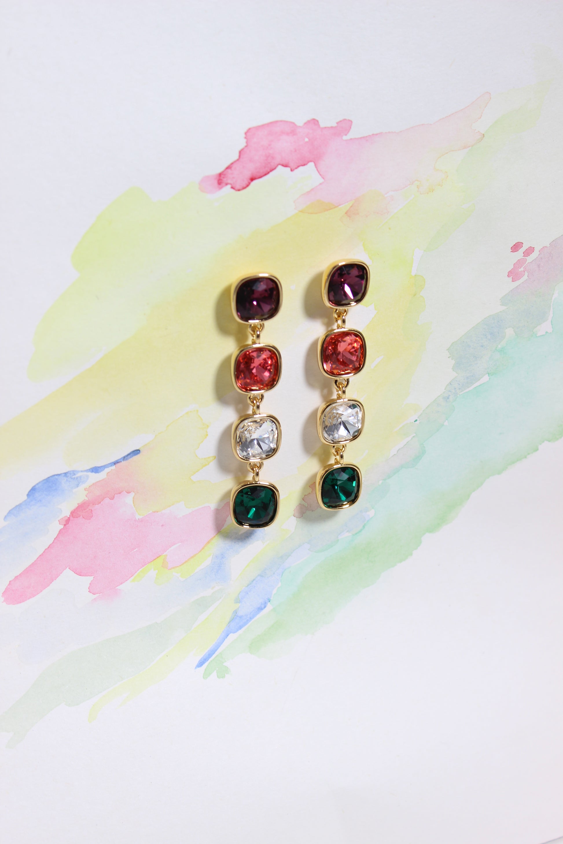 Pair of Rosette Meadow Earrings with colorful gemstones on a watercolor background