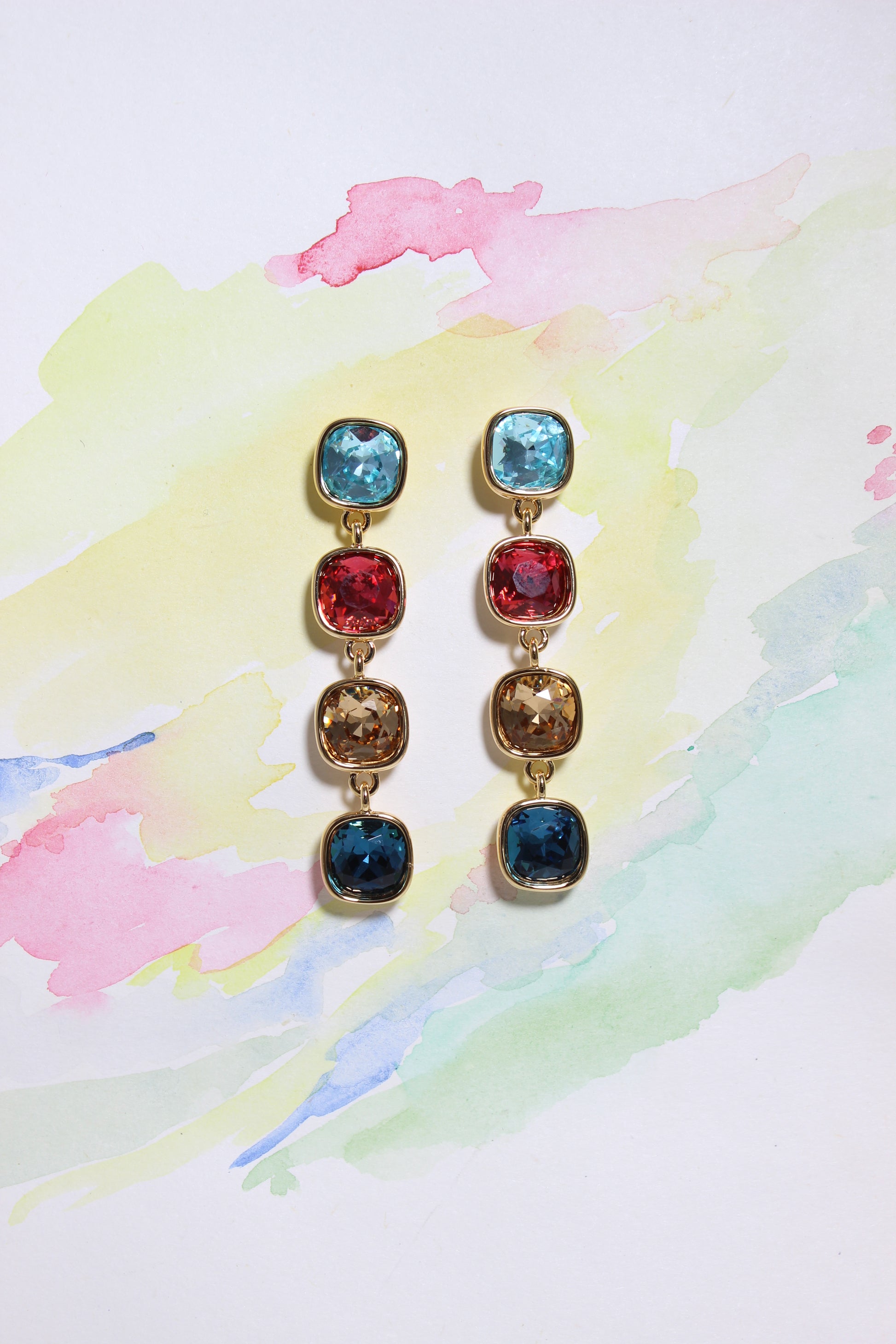 Set of Radiant Skies Earrings with colorful gemstones on a watercolor background
