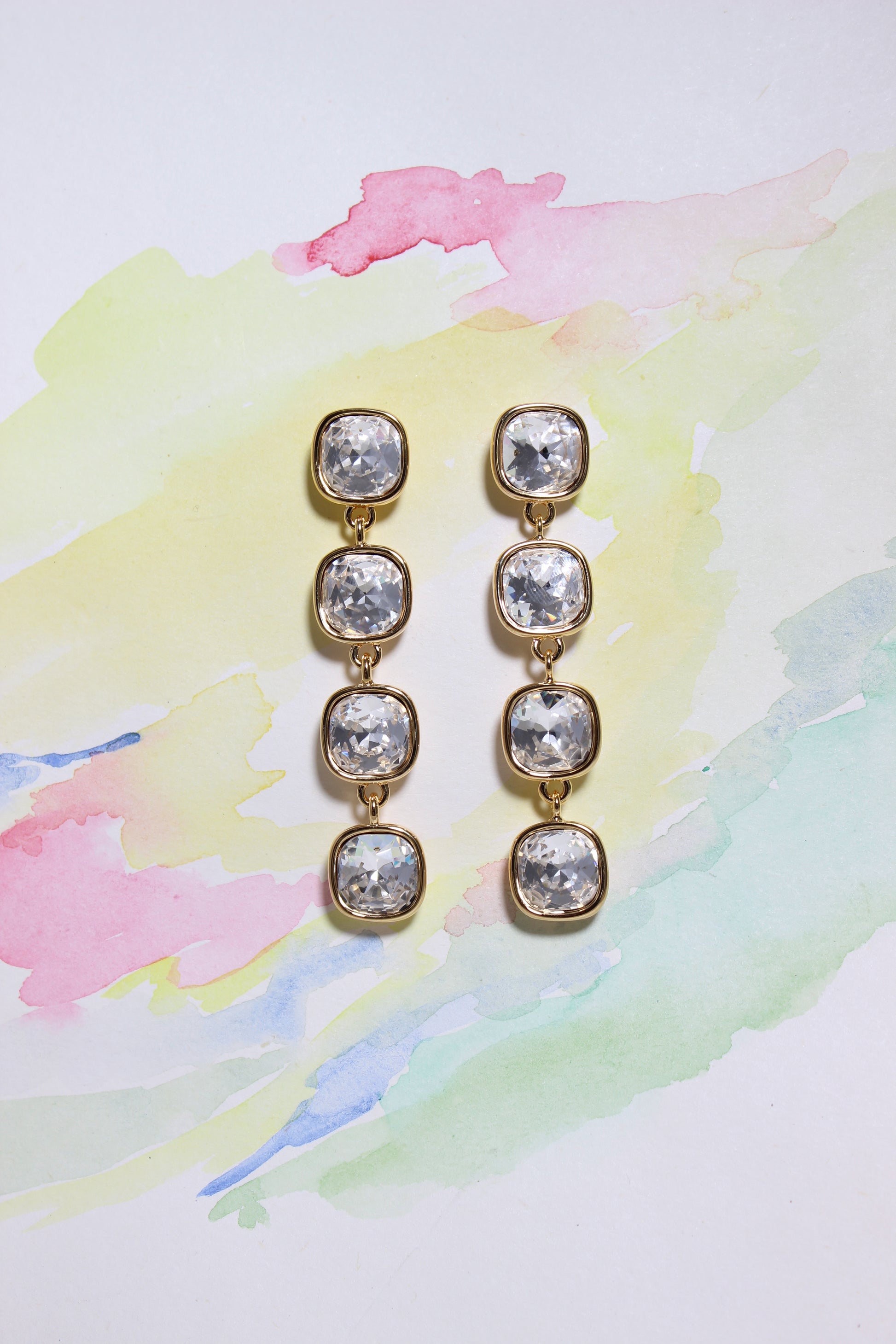 Pair of Glacier Glow Earrings on a colorful watercolor background