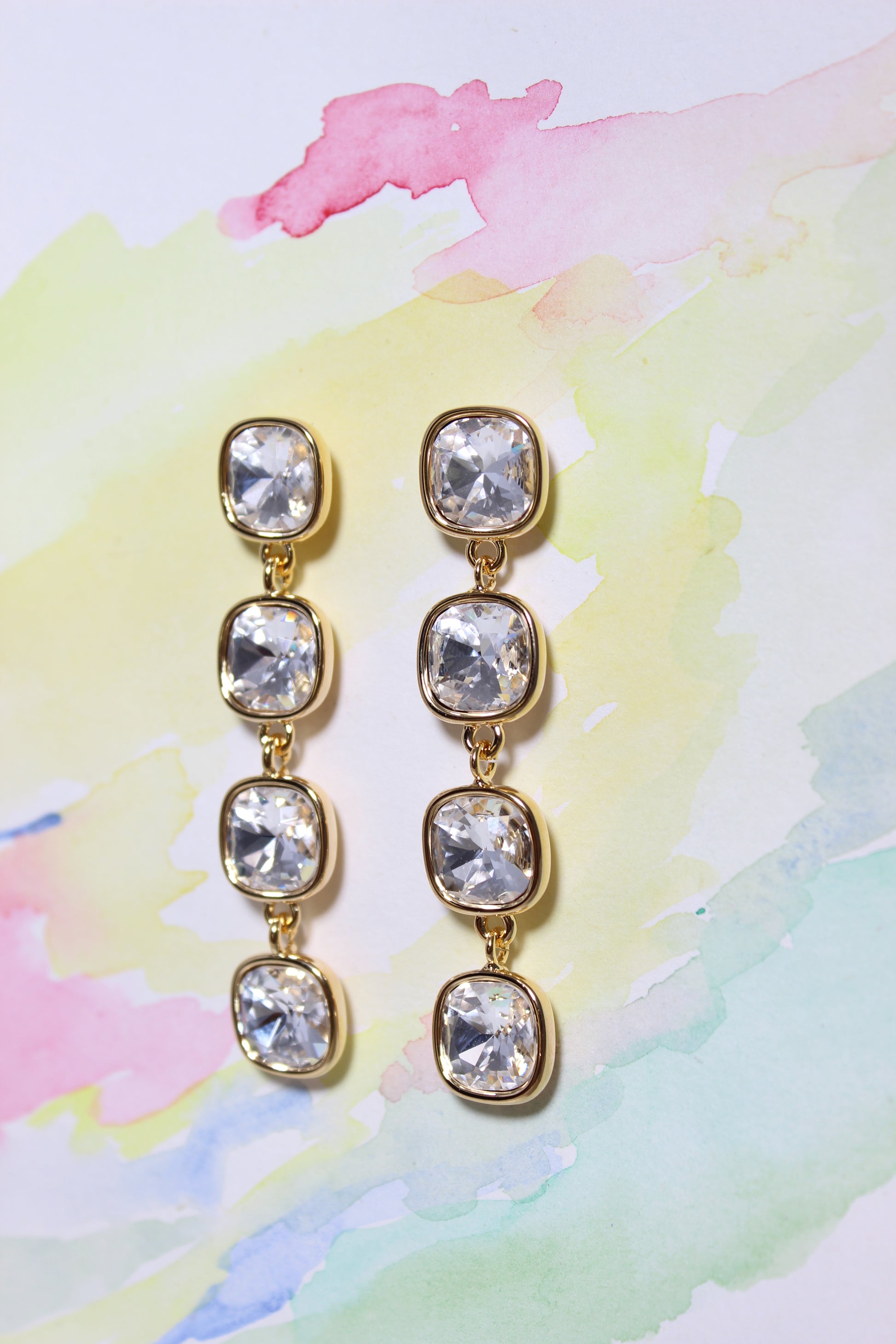 Glacier Glow Earrings with clear gemstones on a watercolor background