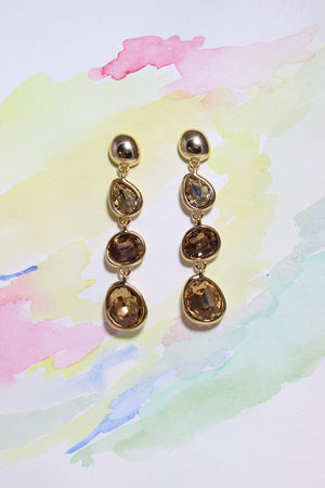 Pair of gold Honeyfall Earrings with smoky stones on a watercolor background
