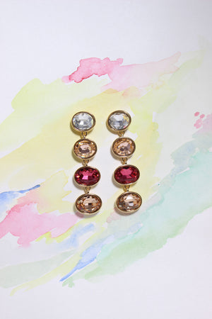 Pair of Radiance Veil Earrings with multicolored gemstones on a watercolor background