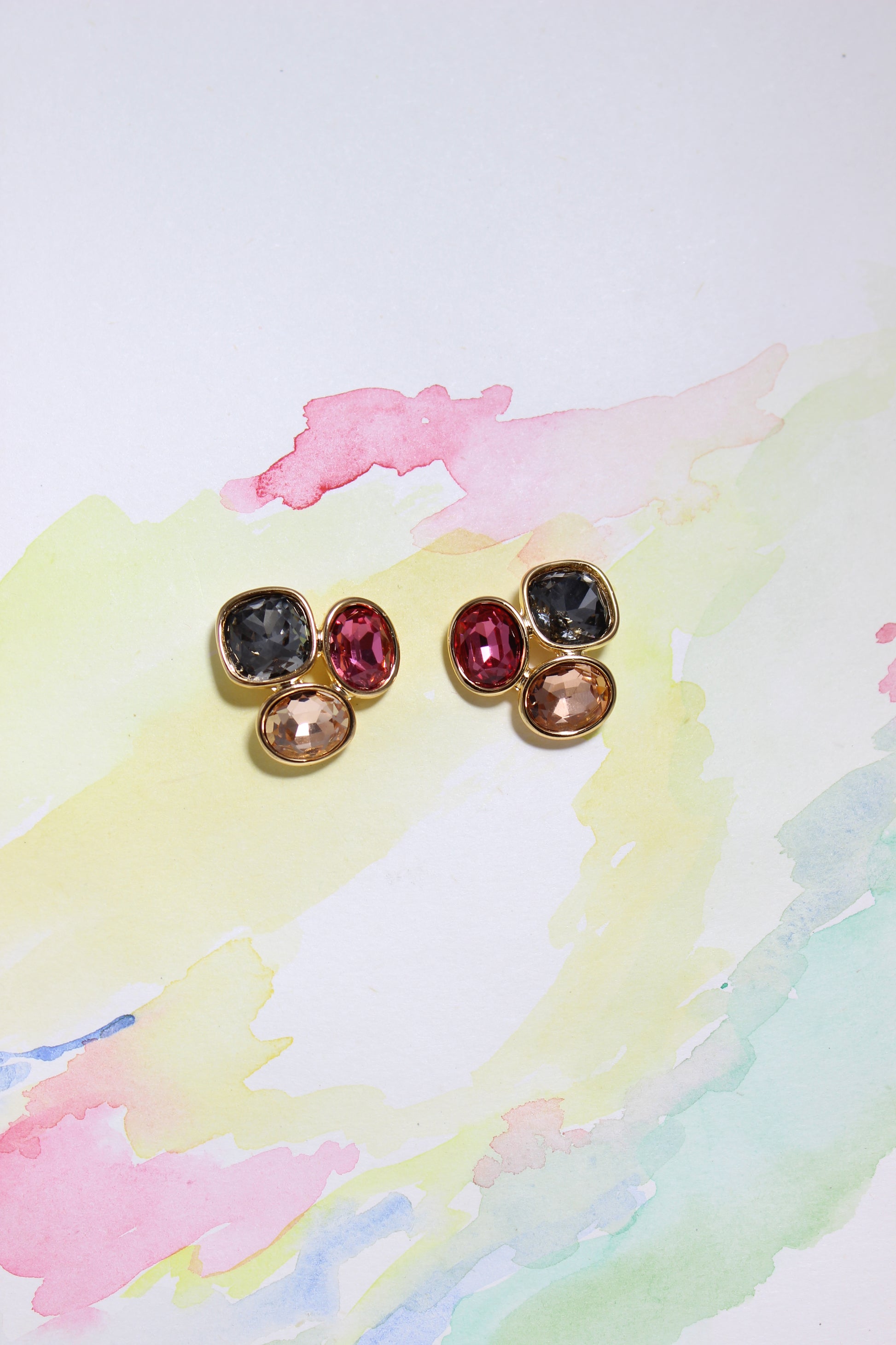 Pair of Solar Gleam Earrings with gemstones on a watercolor background