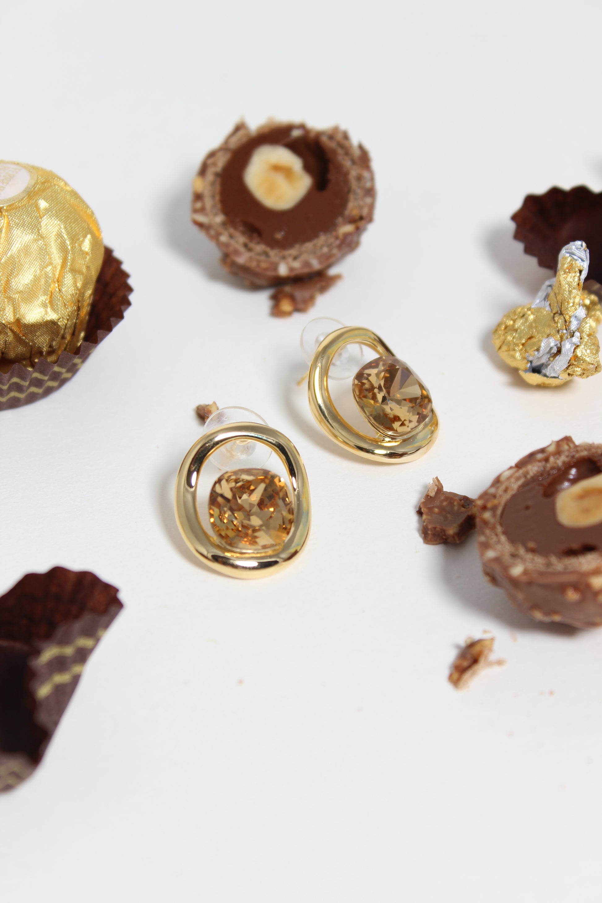 Golden Truffle Earrings on top of chocolate truffles on a white background