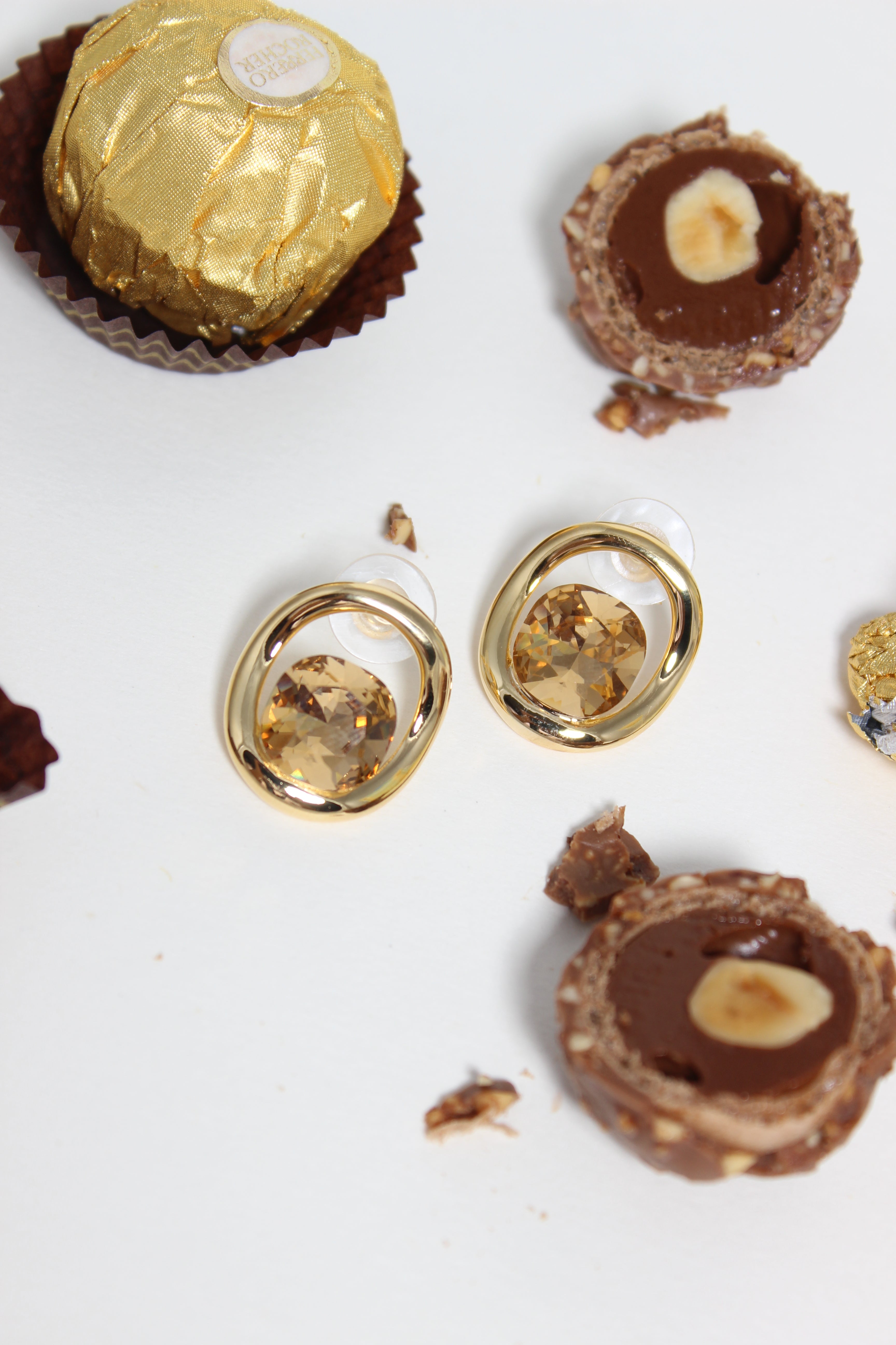 Golden Truffle Earrings on a white background with chocolates 