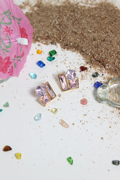 Blush Glow Earrings on a white surface with sand