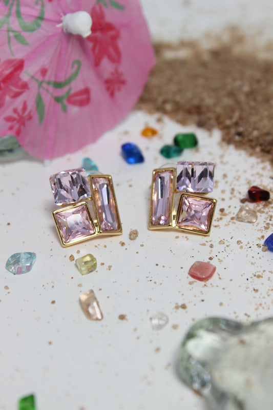 Blush Glow Earrings on a textured surface with colorful stones and an umbrella