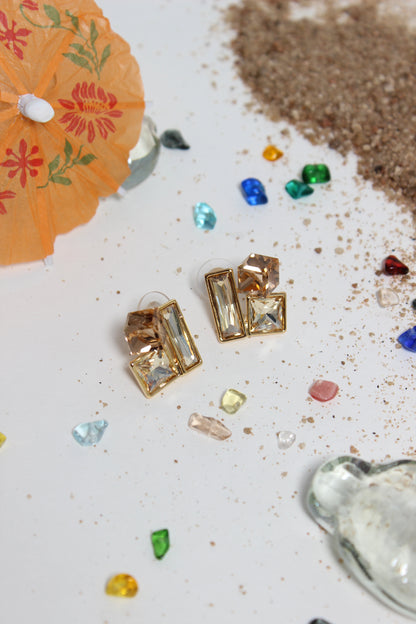 Copper Glow Earrings on a textured surface with colorful stones and an orange paper umbrella