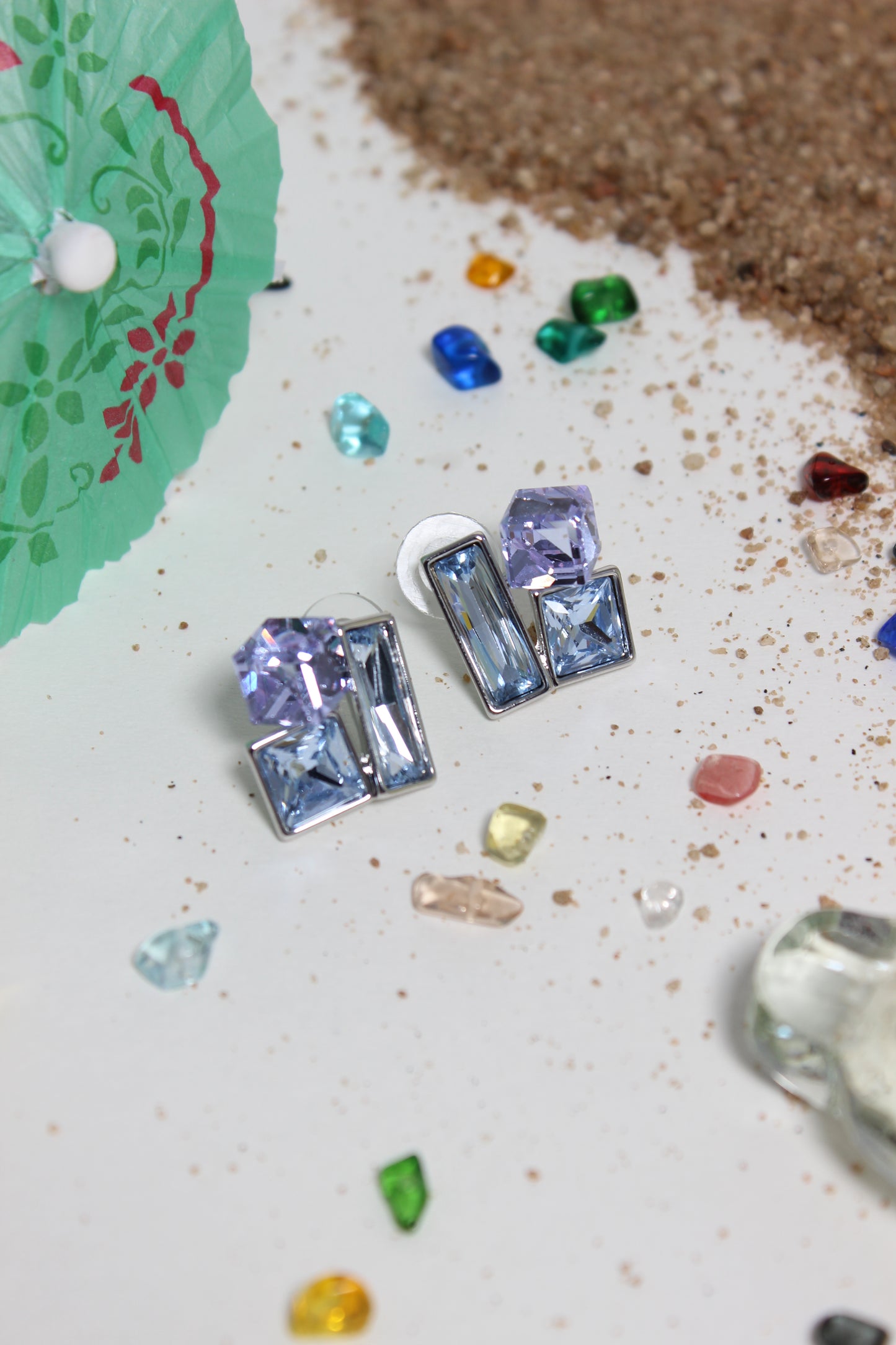 Twilight Glow Earrings on a textured surface with colorful gemstones around