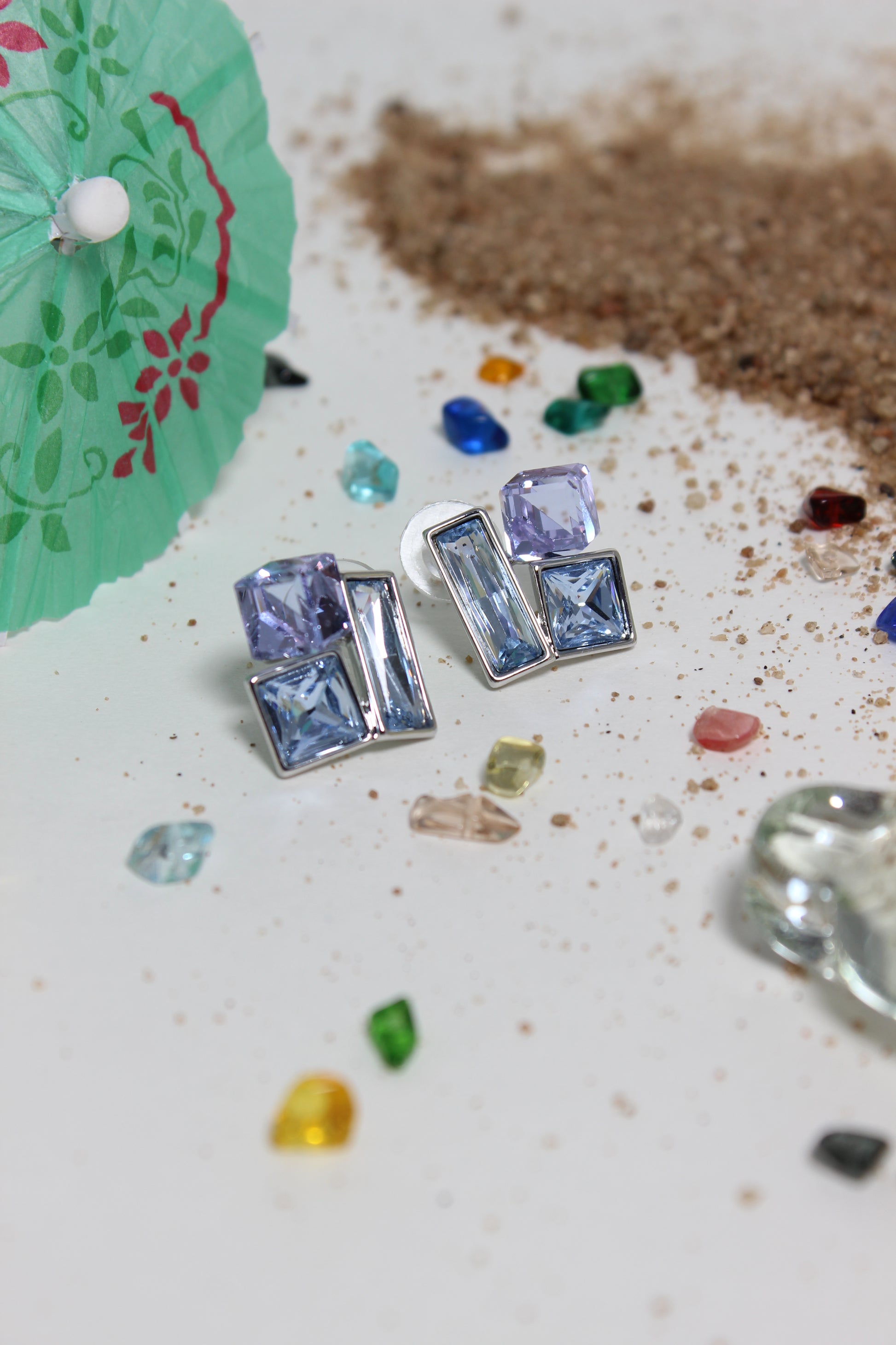 Twilight Glow Earrings on a textured surface with small colored stones