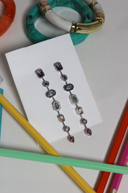 Argent Pastel Pour Earrings on a white card, surrounded by colorful pencils