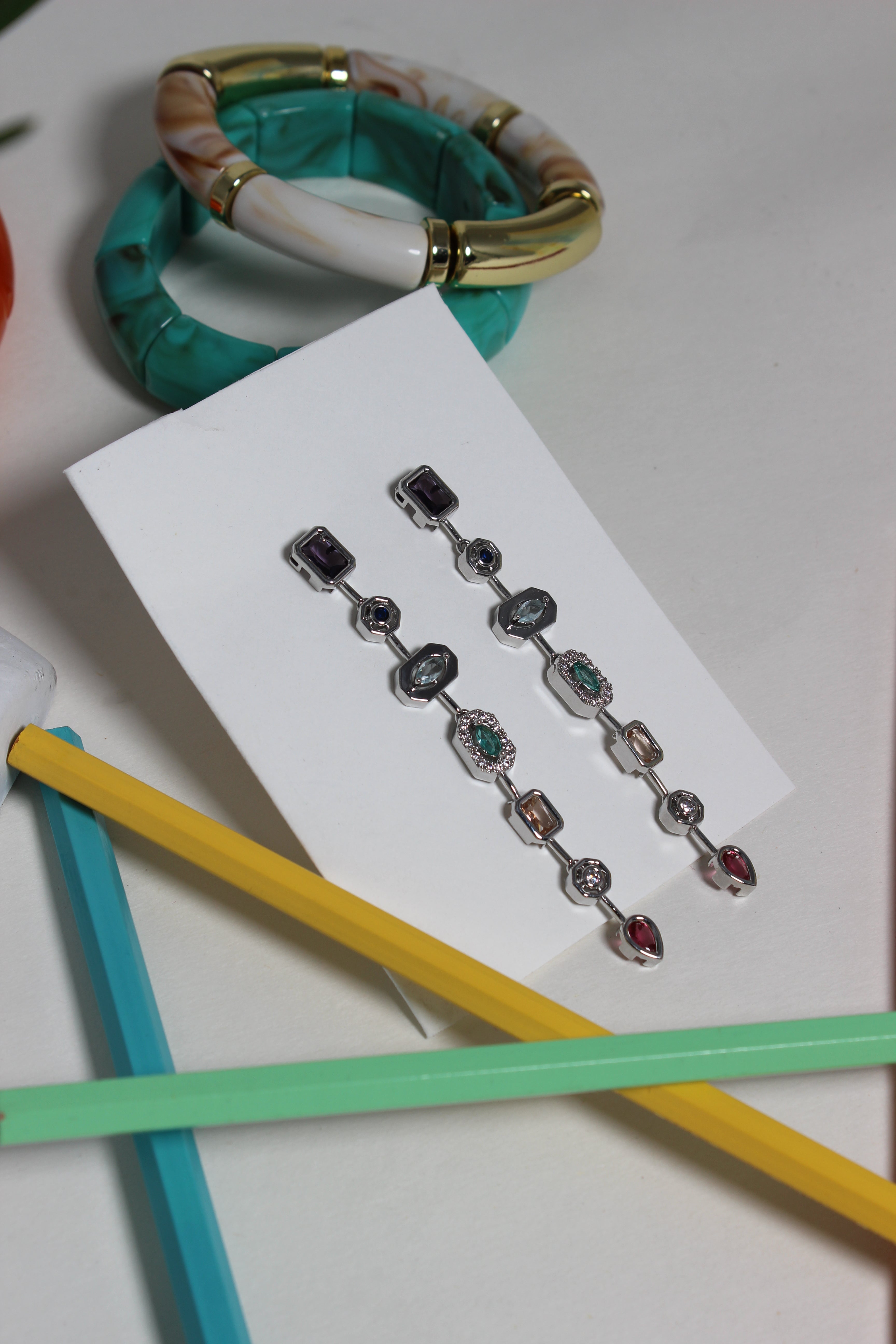 Argent Pastel Pour Earrings on a white card with colorful pencils in the background
