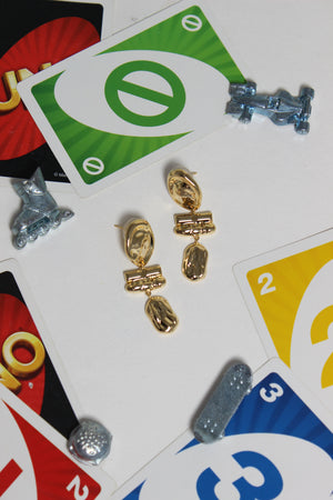 Athena Earrings on a surface with playing cards and small metallic cars