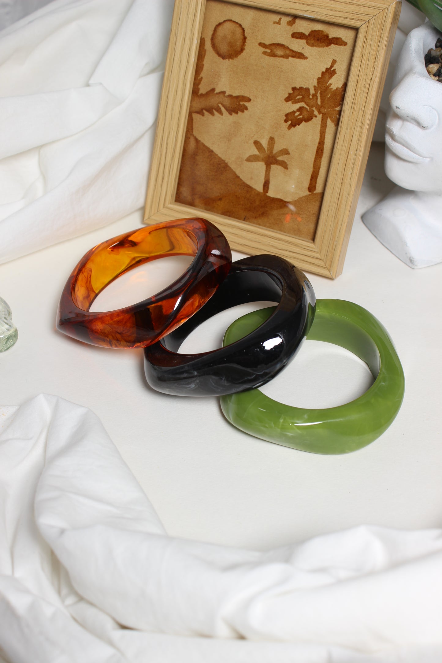 Aurora Stacks Resin Bangles on a white surface with a wooden frame