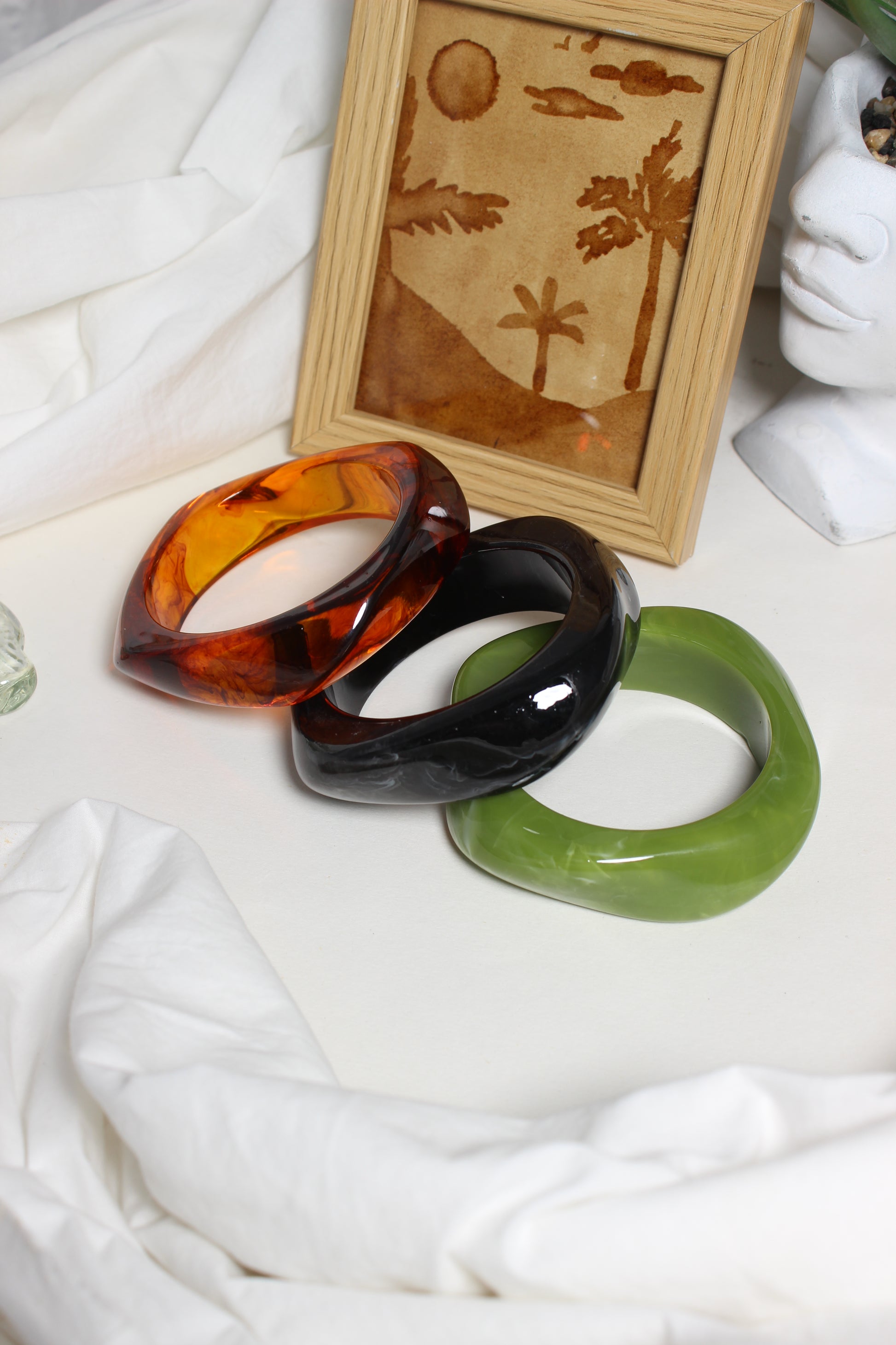 Aurora Stacks Resin Bangles on a white surface with a wooden frame