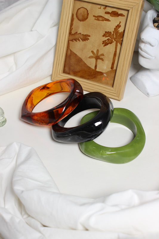 Aurora Stacks Resin Bangles on a white surface with a wooden frame