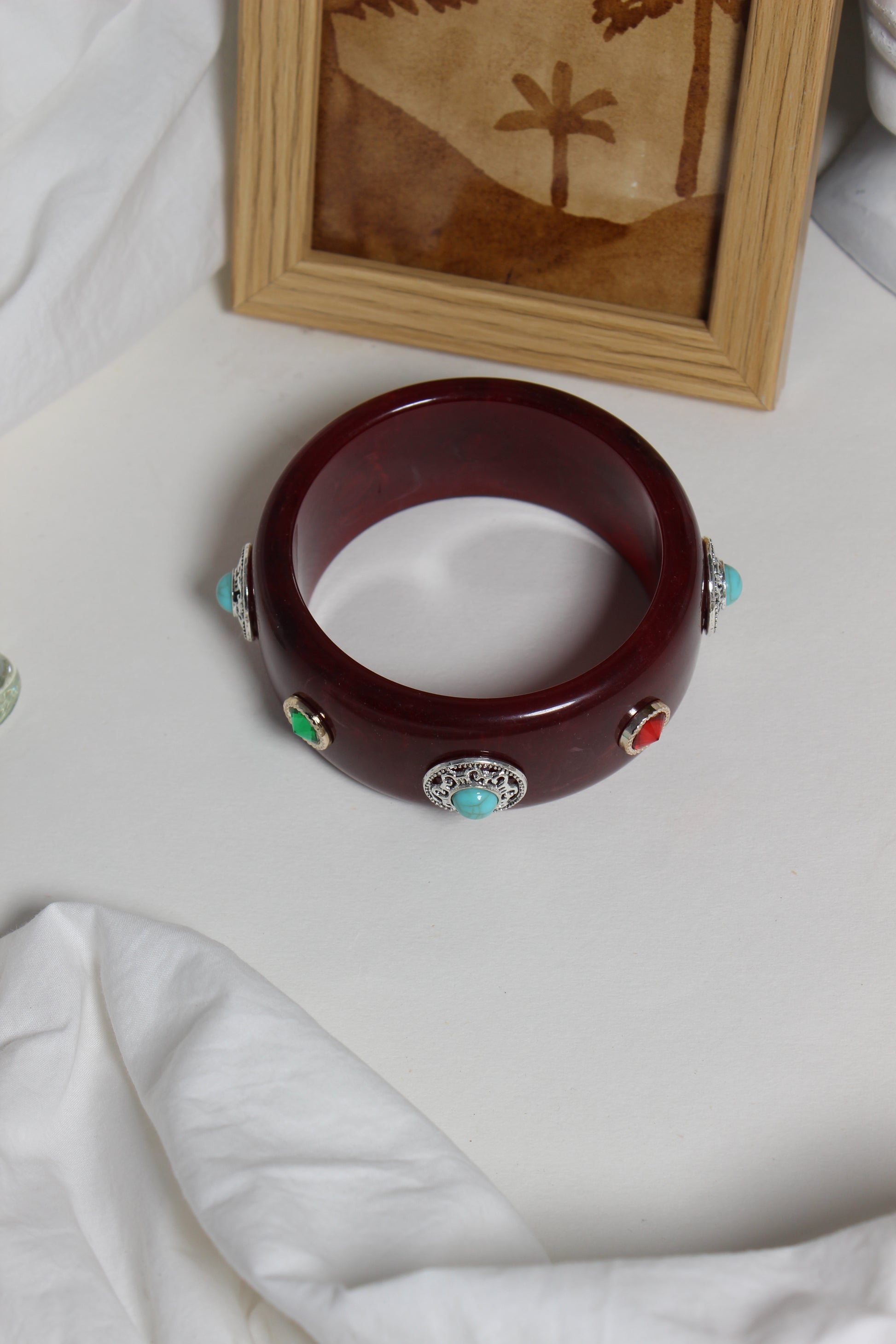 Regalia Bangle on a white surface next to a wooden frame