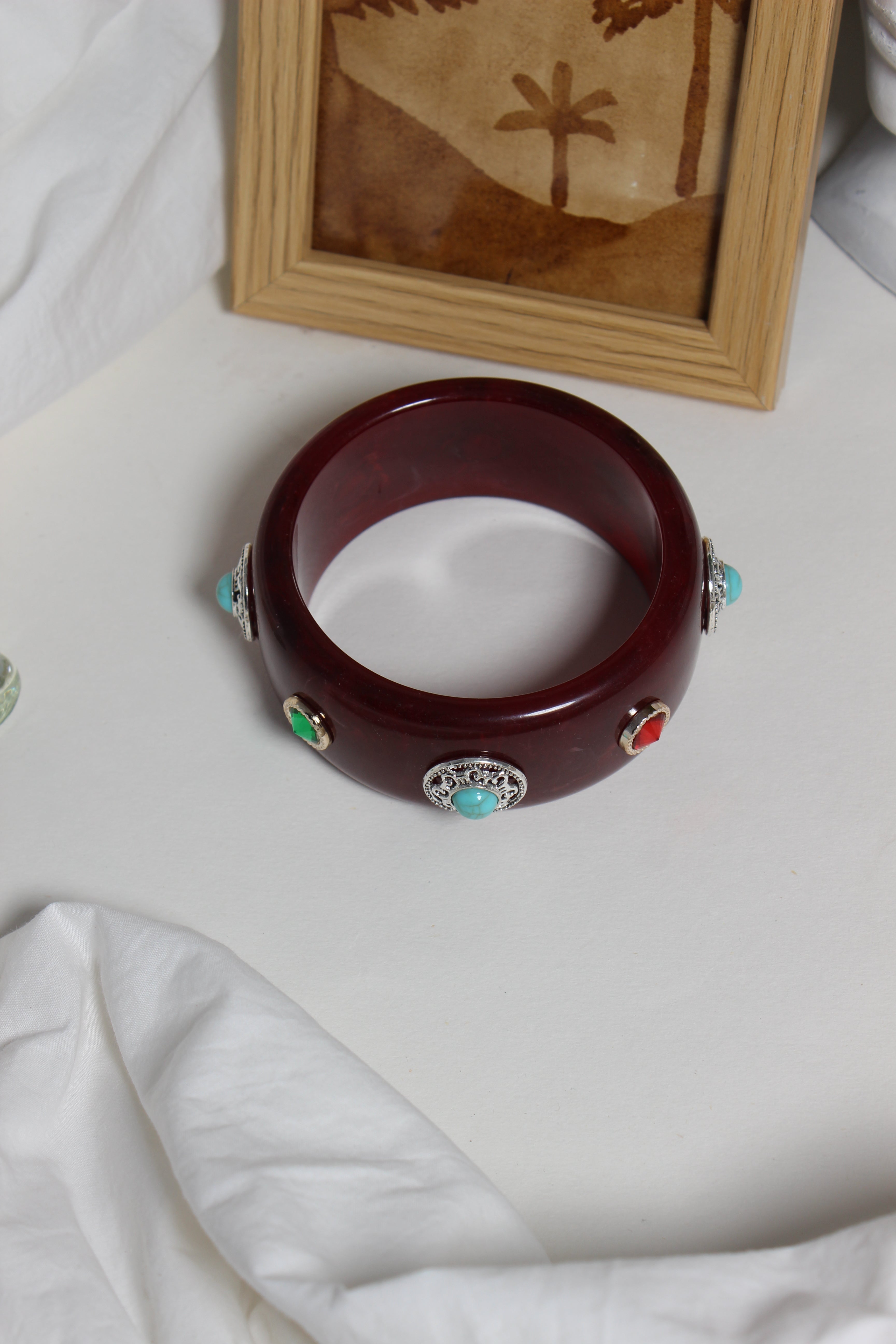 Regalia Bangle on a white surface next to a wooden frame