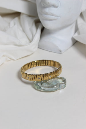 Gold and clear glass Midnight Spark Bracelet on a white surface