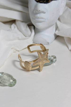 Golden Tide Cuff Bracelet on a white surface with a blurred background