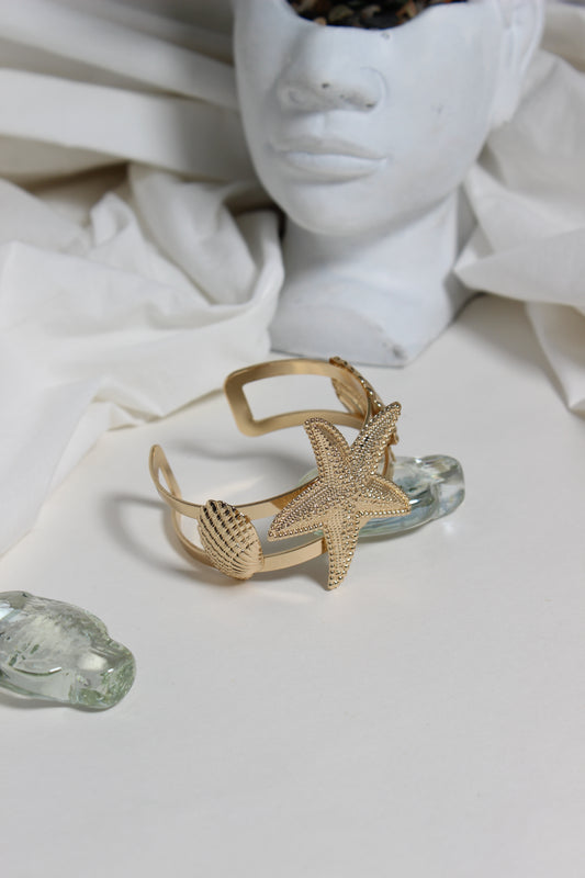 Golden Tide Cuff Bracelet on a white surface with a blurred background