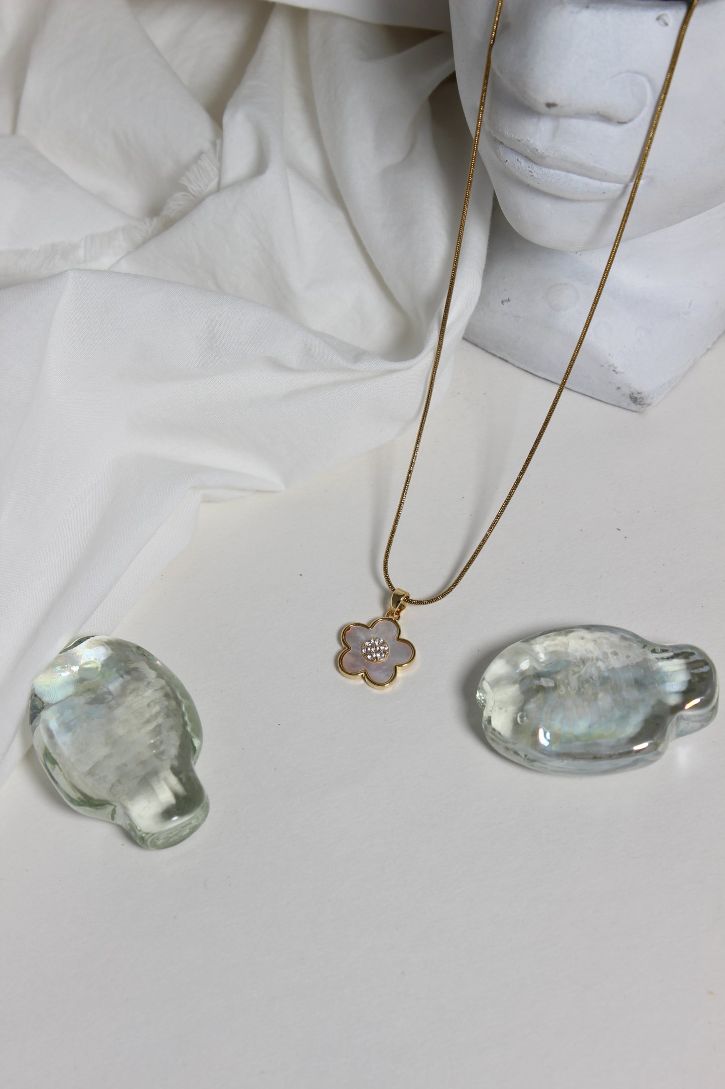 Gold Moonflower Pendant Necklace with a pendant on a white fabric background