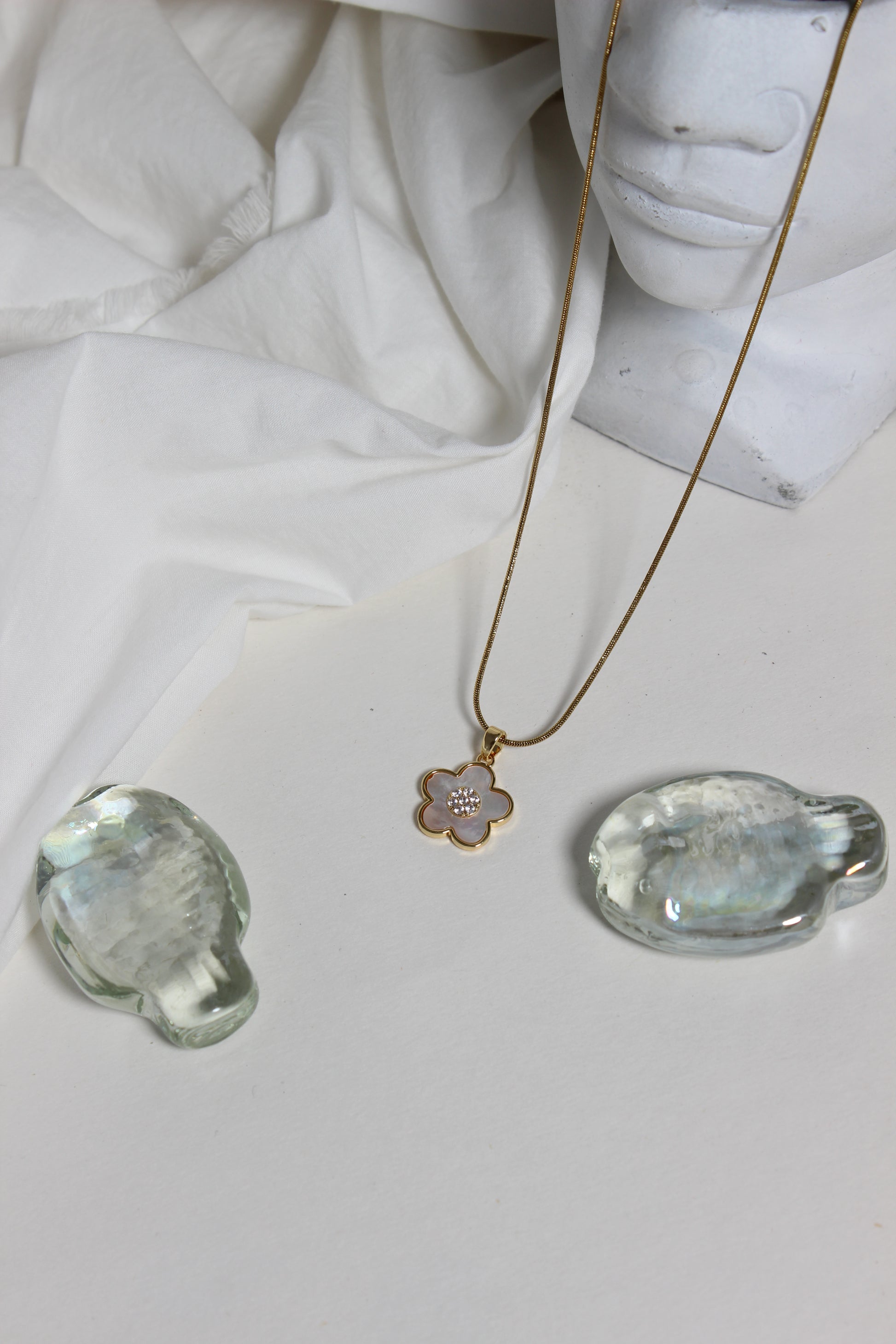 Gold Moonflower Pendant Necklace with a pendant on a white fabric background