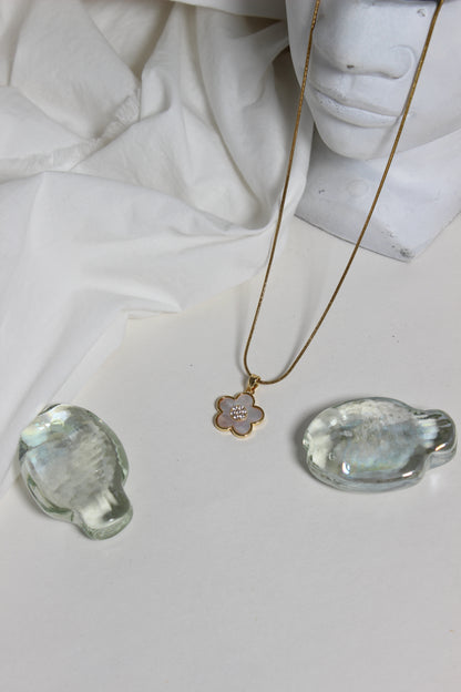 Gold Moonflower Pendant Necklace with a pendant on a white fabric background