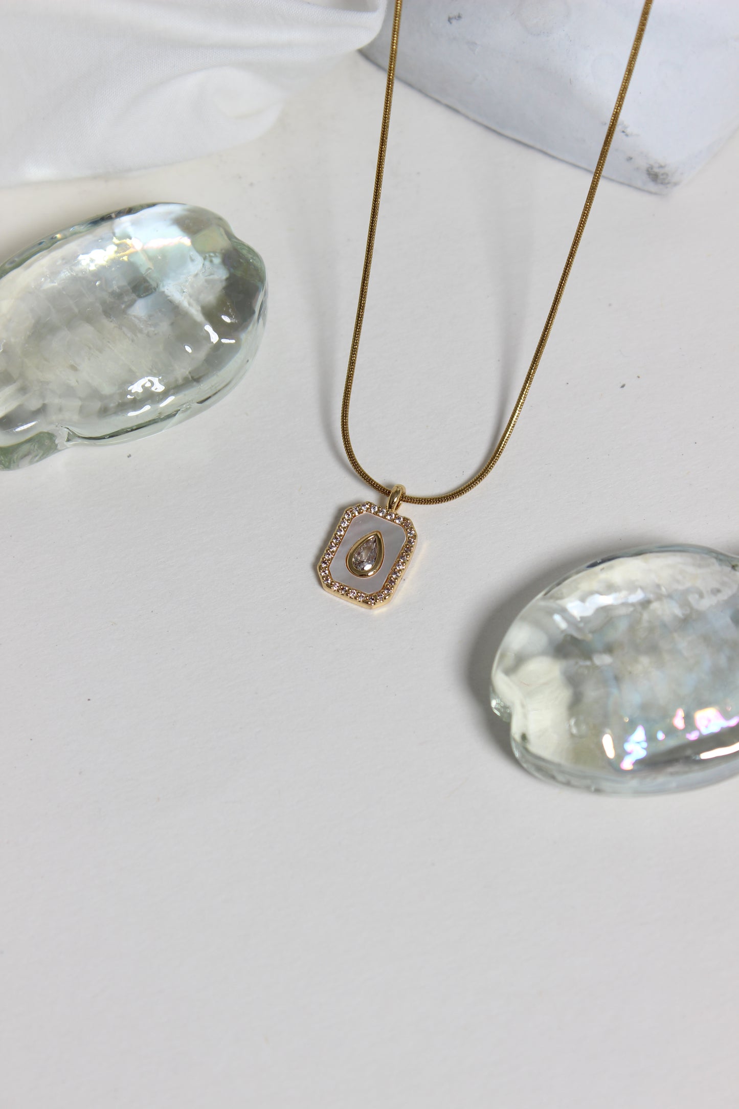 Oro Emeraude Glow Pendant Necklace on a white surface
