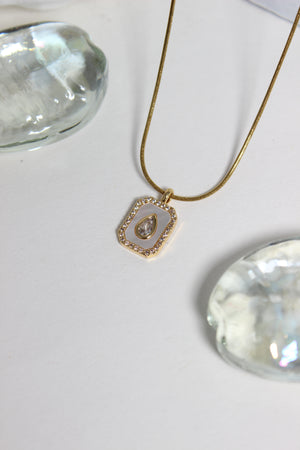 Oro Emeraude Glow Pendant Necklace on a white background with seashell 