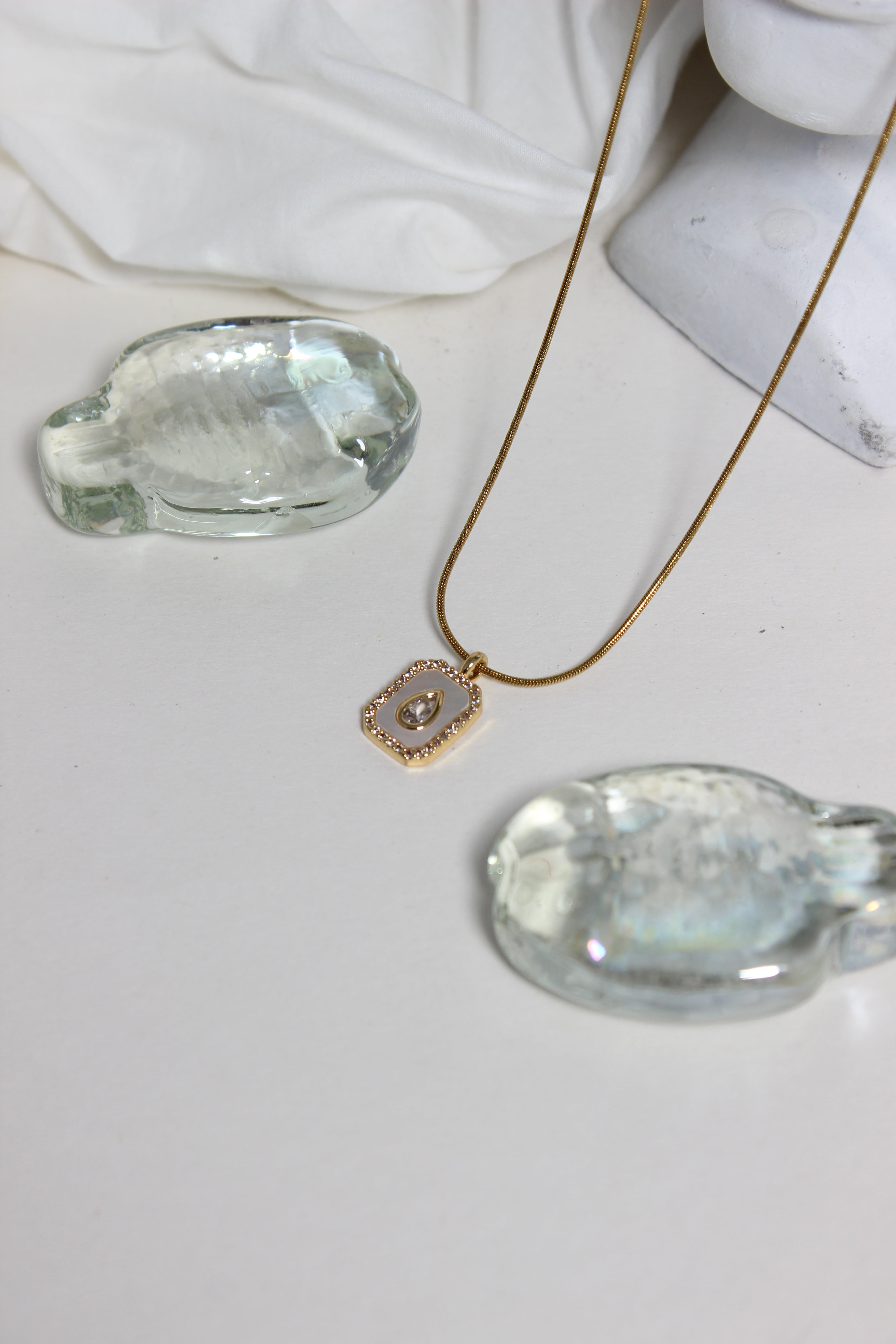 Oro Emeraude Glow Pendant Necklace with green gemstones and a gold pendant on a white background