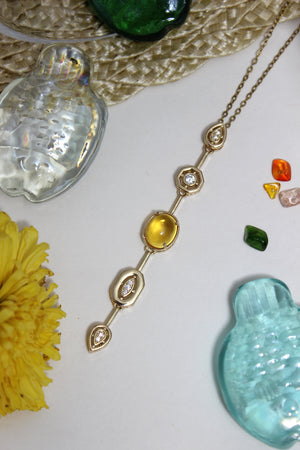 Coralie Necklace on a textured surface with flowers and shells