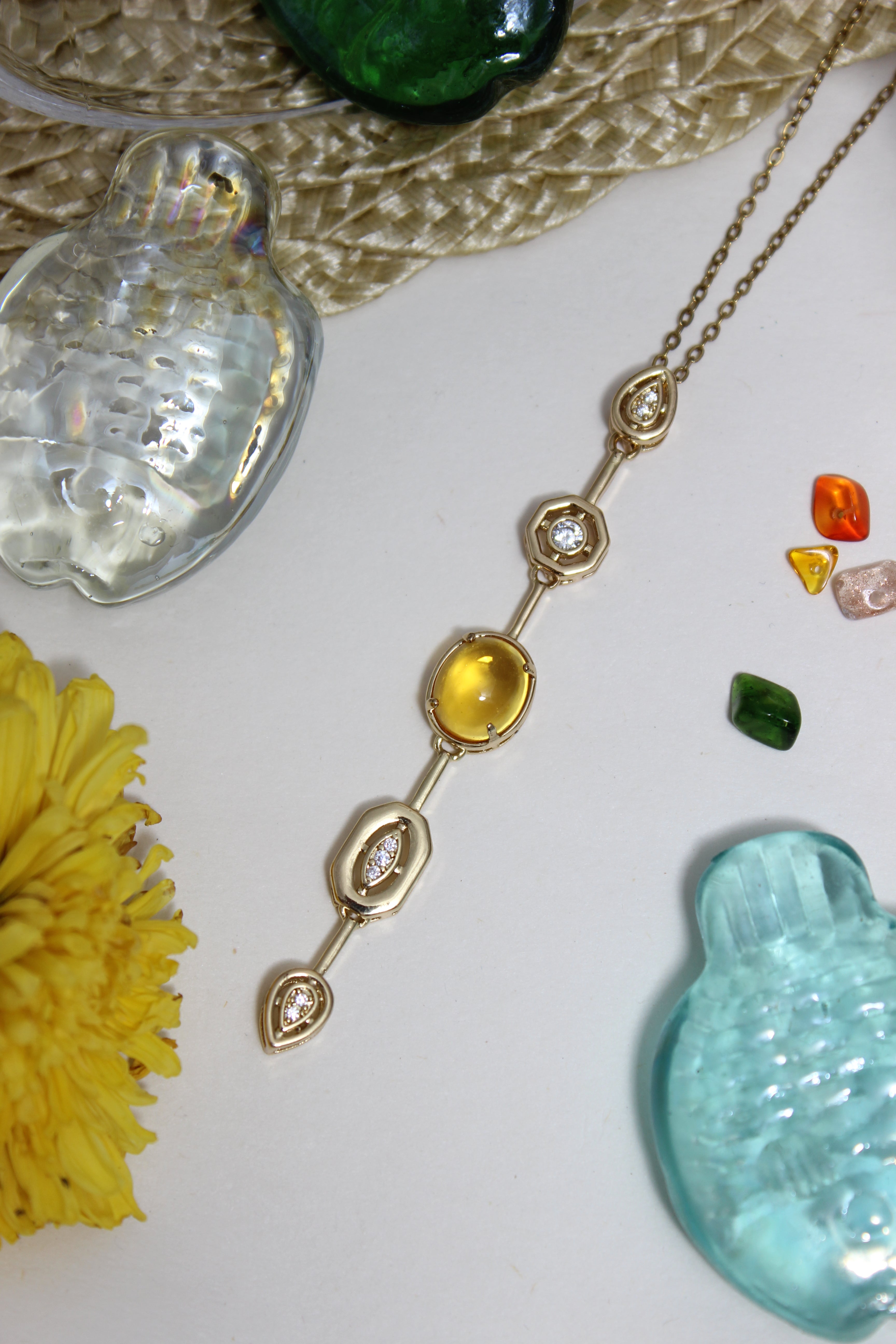 Coralie Necklace on a textured surface with flowers and shells