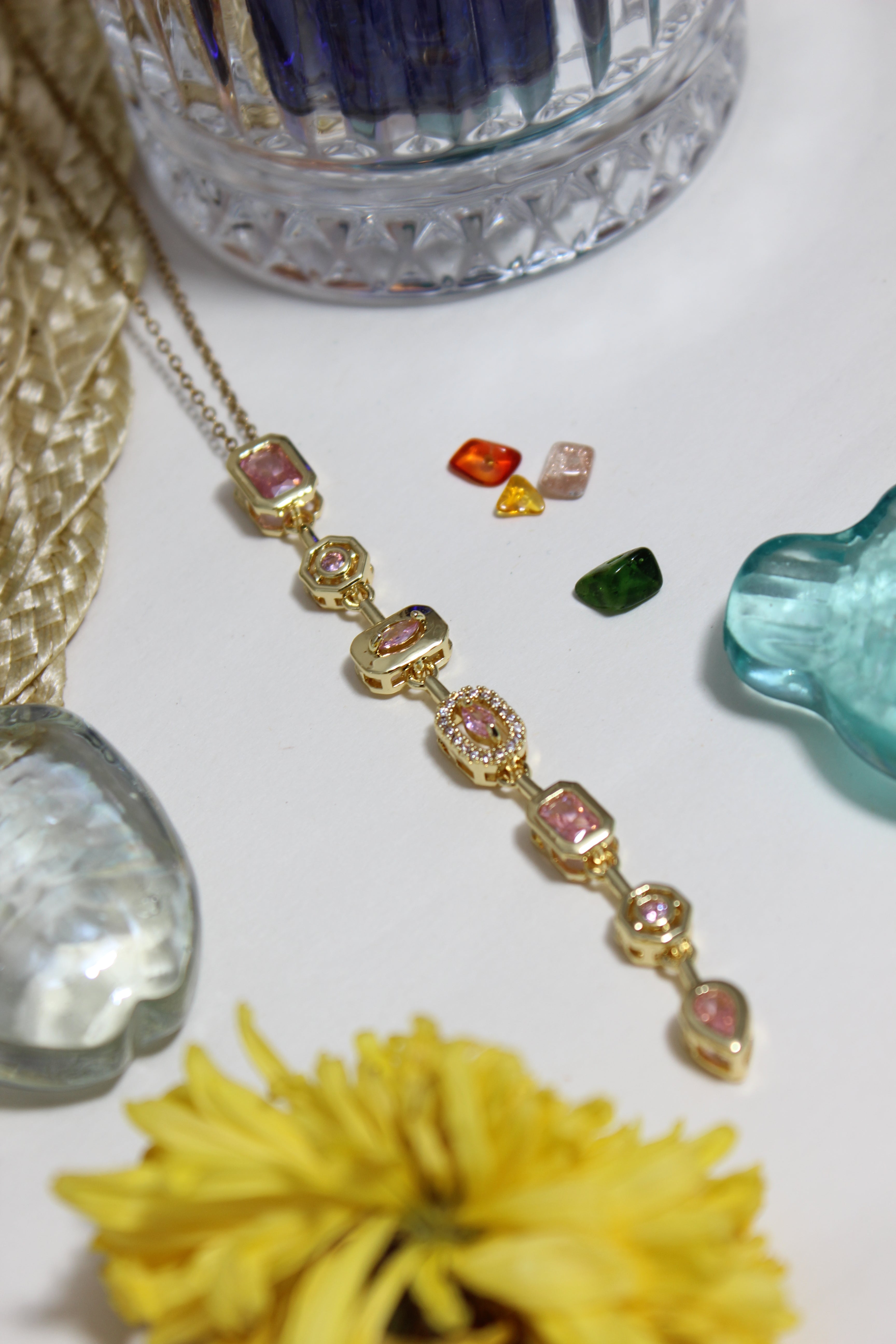 Blush Pastel Pour Necklace on a white surface with decorative stones